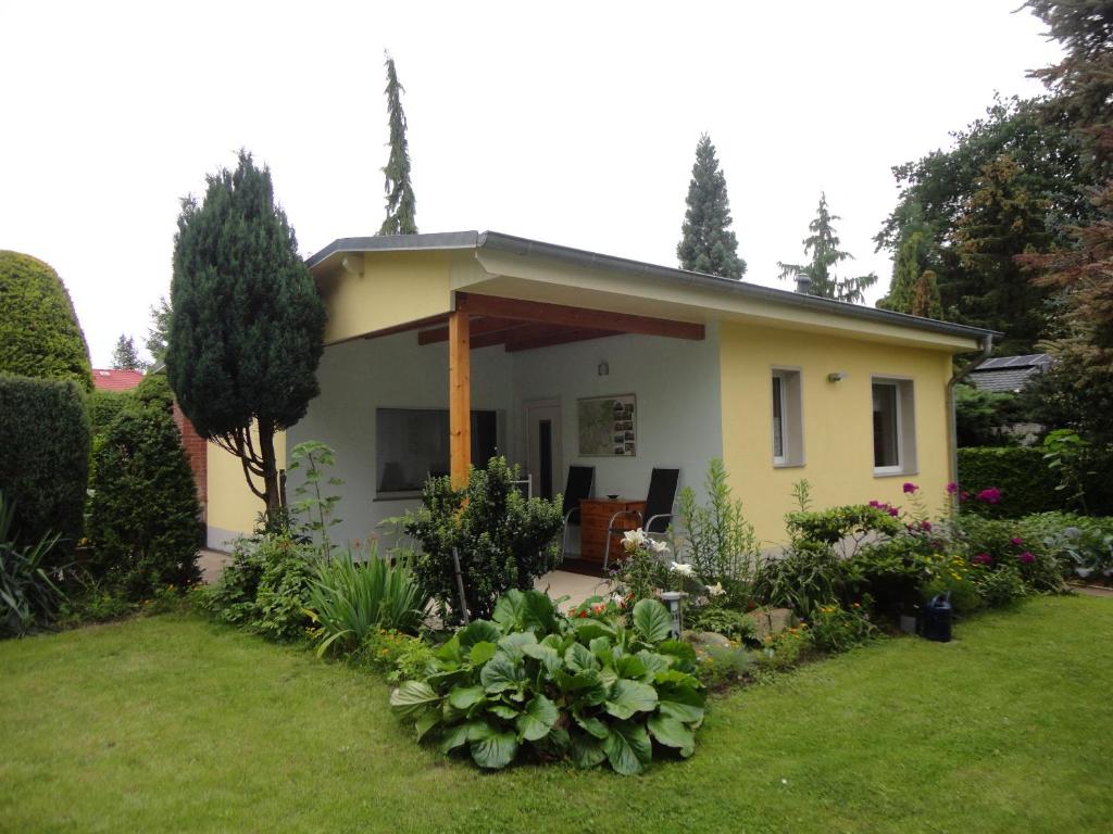 una pequeña casa amarilla con un patio de césped en Sommerhaus im Grünen en Berlín