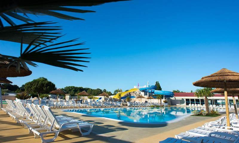a pool with chairs and umbrellas on a resort at Les Mathes in Les Mathes