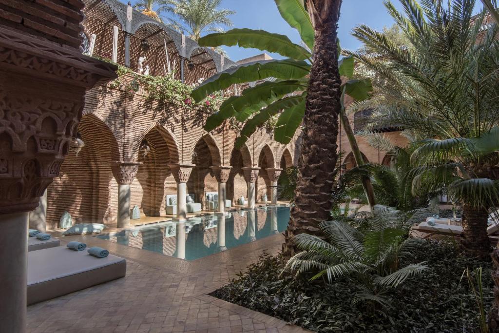 una piscina con palme in un edificio di La Sultana Marrakech a Marrakech