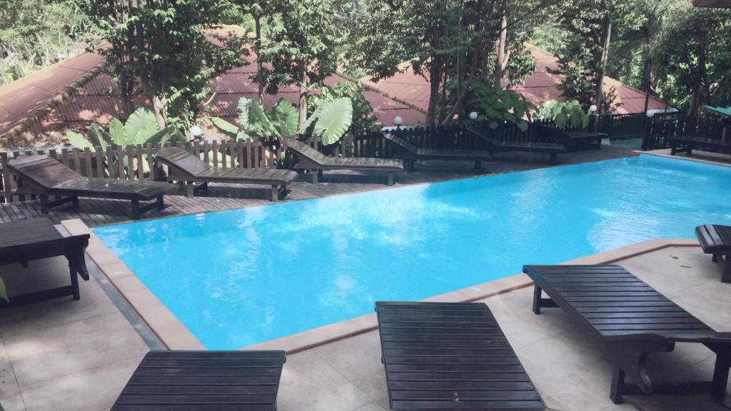 uma grande piscina azul com bancos e mesas em JJ Bungalow em Phi Phi Don