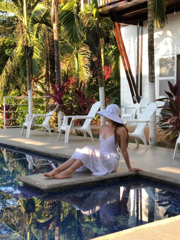 a woman in a white dress sitting next to a swimming pool at Hotel Ballena Dorada in Uvita