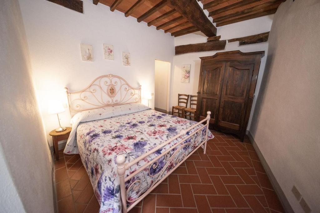a bedroom with a bed with a floral bedspread at Casa Selvolini - VOLPAIA in Radda in Chianti