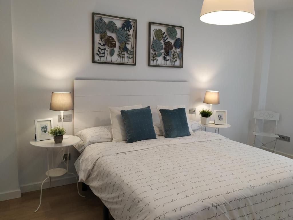 een slaapkamer met een groot wit bed en 2 tafels bij Apartamento OD in Piedras Blancas
