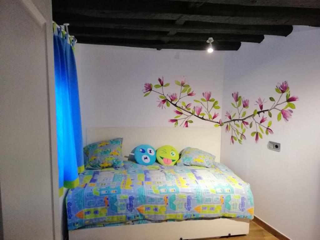 ein Schlafzimmer mit einem Bett mit einem Baum an der Wand in der Unterkunft Apartamentos El Greco in Toledo