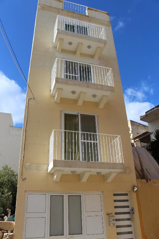 a yellow building with a balcony and a window at All Nations Holiday Home in Għajnsielem