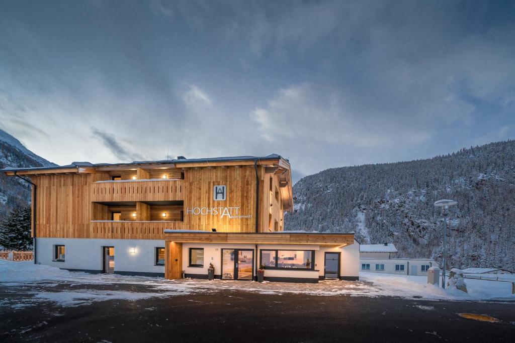 a large wooden building with snow on the ground at Hochstatt Appartements in Sölden