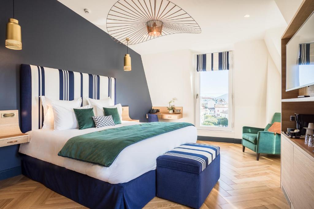 um quarto com uma cama grande e uma parede azul em Hôtel & Spa Madison Saint Jean de Luz em Saint-Jean-de-Luz