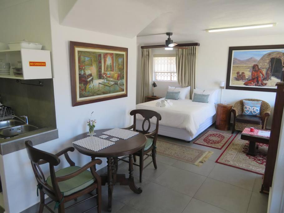 a bedroom with a bed and a table and a kitchen at Dawn's Place in Hermanus