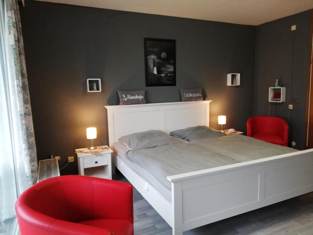um quarto com uma cama branca e uma cadeira vermelha em Büsum Nordseestraße 5 EG FeWo em Büsum