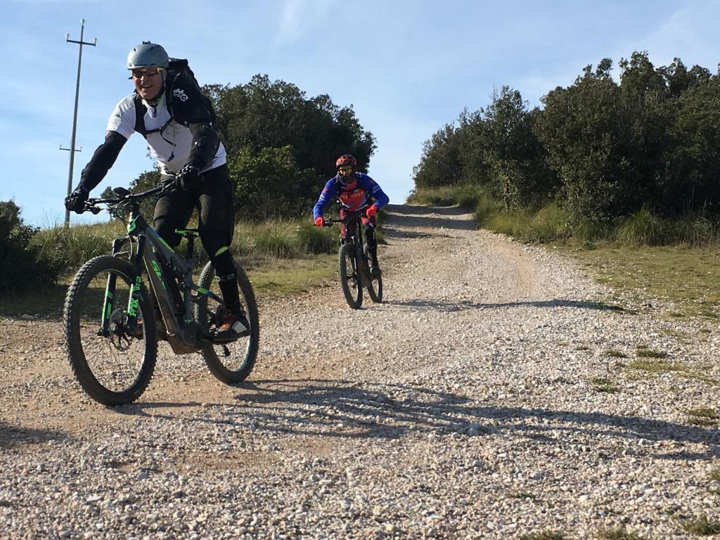 two people riding bikes on a dirt road at Bike&Boat Argentario Hotel in Porto Santo Stefano