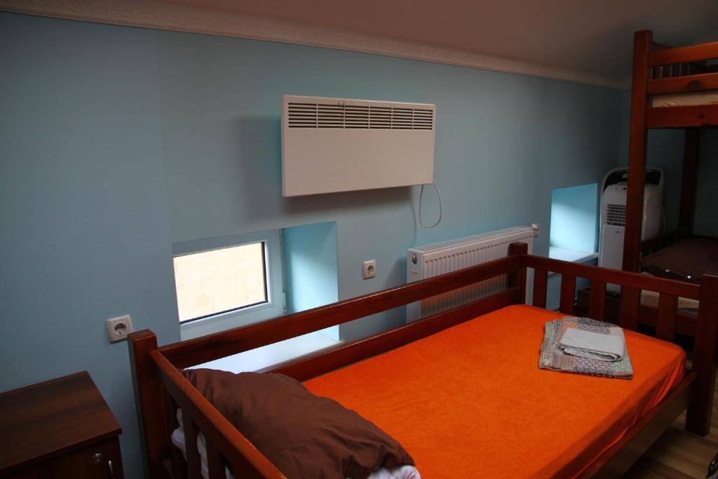 a bedroom with a bed with an orange blanket and a window at Lions Heart Hostel in Lviv