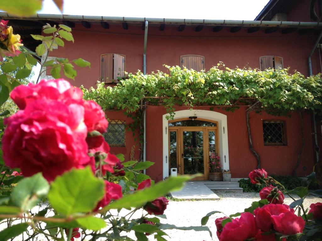 una casa con flores rojas delante de ella en All'Antica Scuderia Del Castello, en Maiano