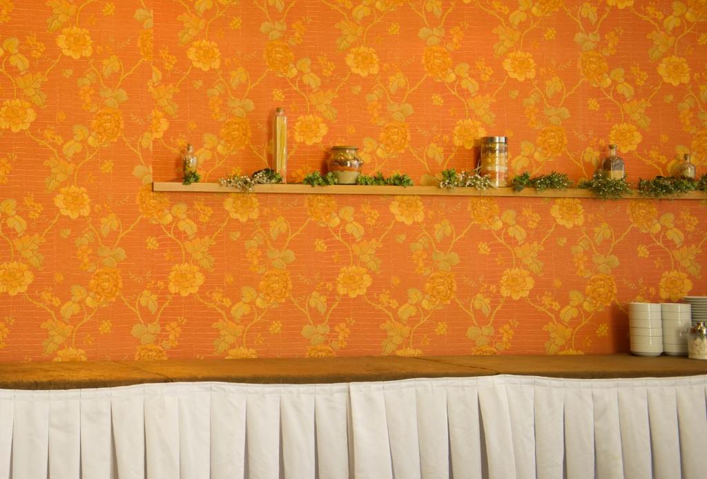 an orange wall with a shelf with flowers on it at Pınar Elite Hotel in Adana