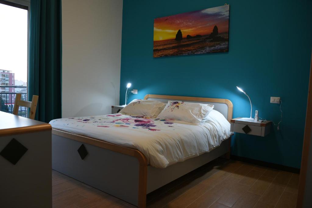 um quarto com uma cama com uma parede azul em La Casa del Viaggiatore em Catânia