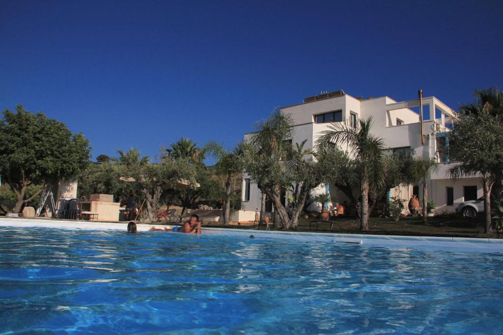 una mujer en una piscina al lado de una casa en Punta Bianca Suite & Home Experience, en Agrigento