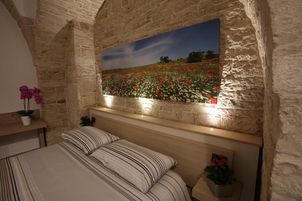 una camera da letto con un letto e un dipinto a fiori sul muro di B&B Arco Caputi a Ruvo di Puglia