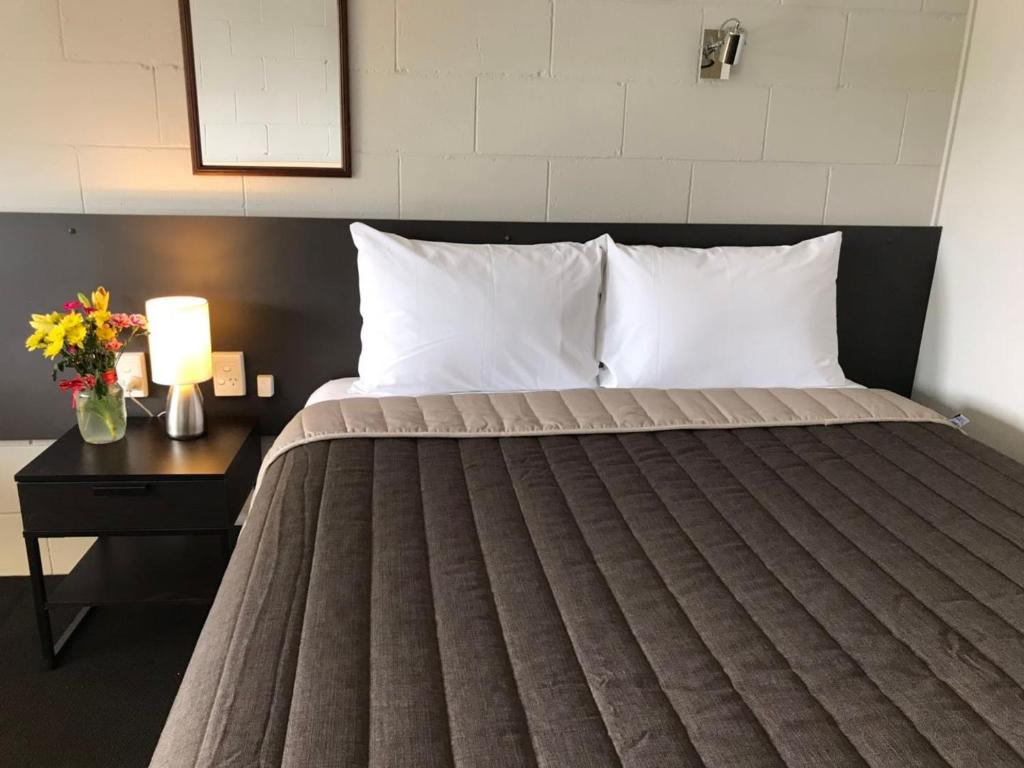 uma cama com almofadas brancas e uma mesa com um candeeiro em Mandalay Motel em Roma