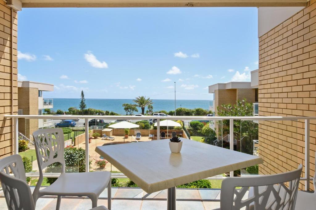 a table and chairs on a balcony with a view of the ocean at 2 Bedroom Top Floor Unit - Ocean Views and Pool in Alexandra Headland