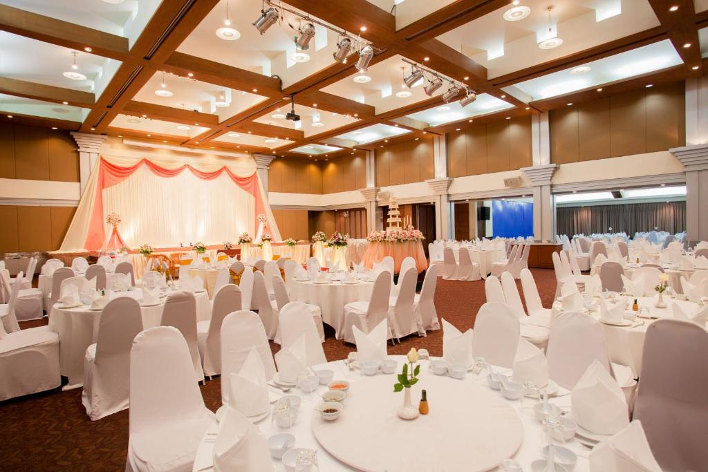 um salão de banquetes com mesas brancas e cadeiras brancas em Phuket Merlin Hotel em Cidade Phuket