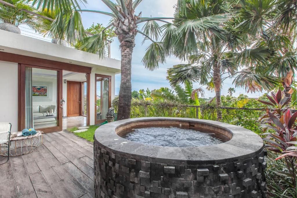 a hot tub on a patio with palm trees at AB Villa & Apartments in Seminyak