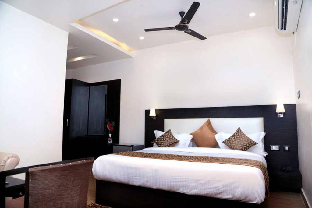 Hotel Vinayak Lifestyle Hotels في لاكناو: غرفة نوم بسرير كبير مع مروحة سقف