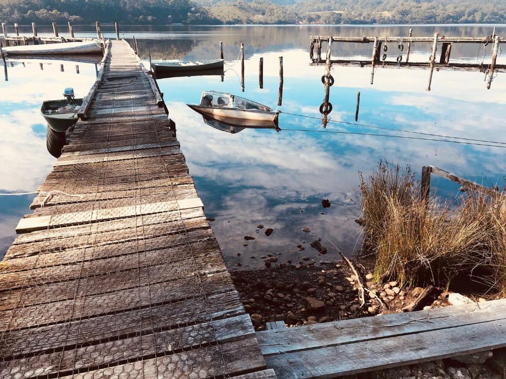 boats are docked at a pier near a body of water at Salt Box Hideaway in Strahan