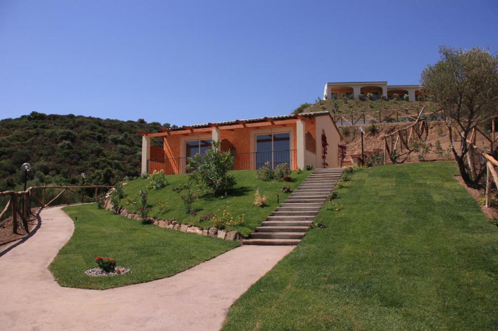 uma casa numa colina com um relvado e um edifício em Hotel Pedra Ruja em Budoni