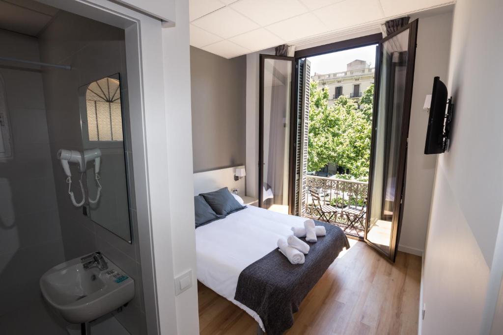 a bedroom with a bed and a sink and a window at Hostalin Barcelona Gran Via in Barcelona