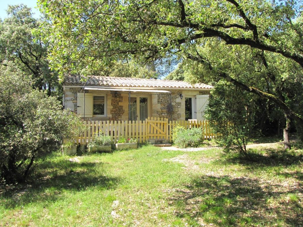 una pequeña casa con una valla en un patio en Domaine du bois gîte Bleuette, en Galargues