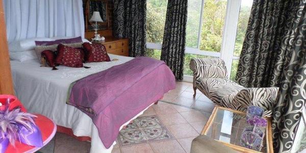 um quarto com uma cama, uma cadeira e uma janela em Isigidi Beach House em Port Shepstone