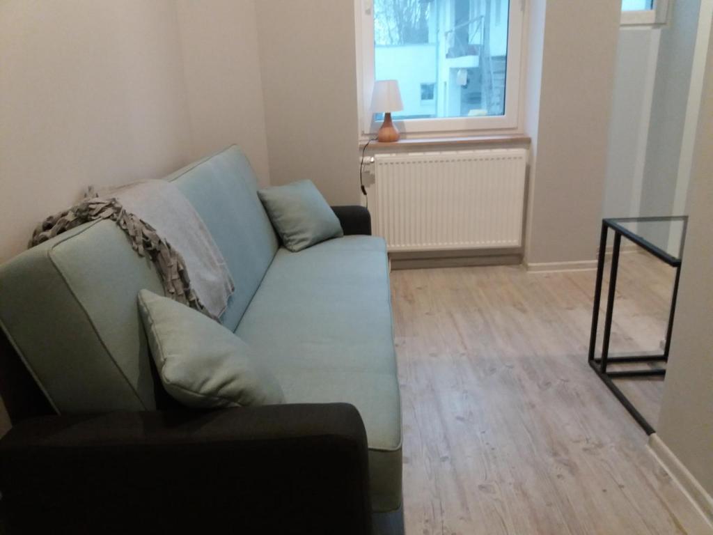 a living room with a blue couch and a window at Business Apartments 1 in Bydgoszcz