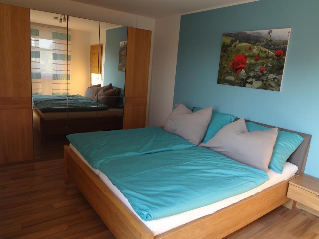 Schlafzimmer mit einem Bett mit blauer Bettwäsche und einem Spiegel in der Unterkunft Weinstraßenapartment Fam. Dietrich in Ratsch an der Weinstraße