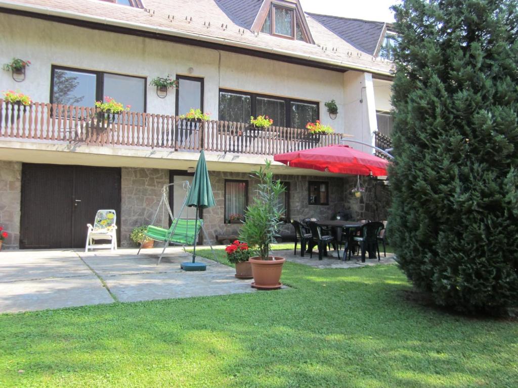 a house with a patio with a table and umbrella at Tóth Vendégház in Parád