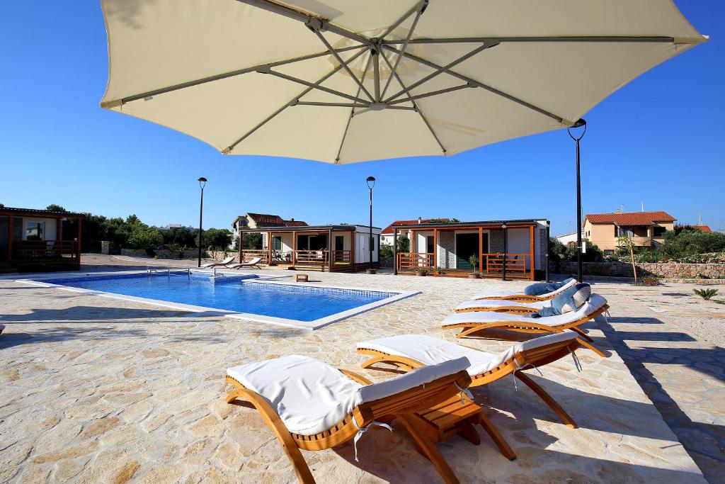 a group of chairs and an umbrella next to a pool at Marina Brugor Murter in Murter