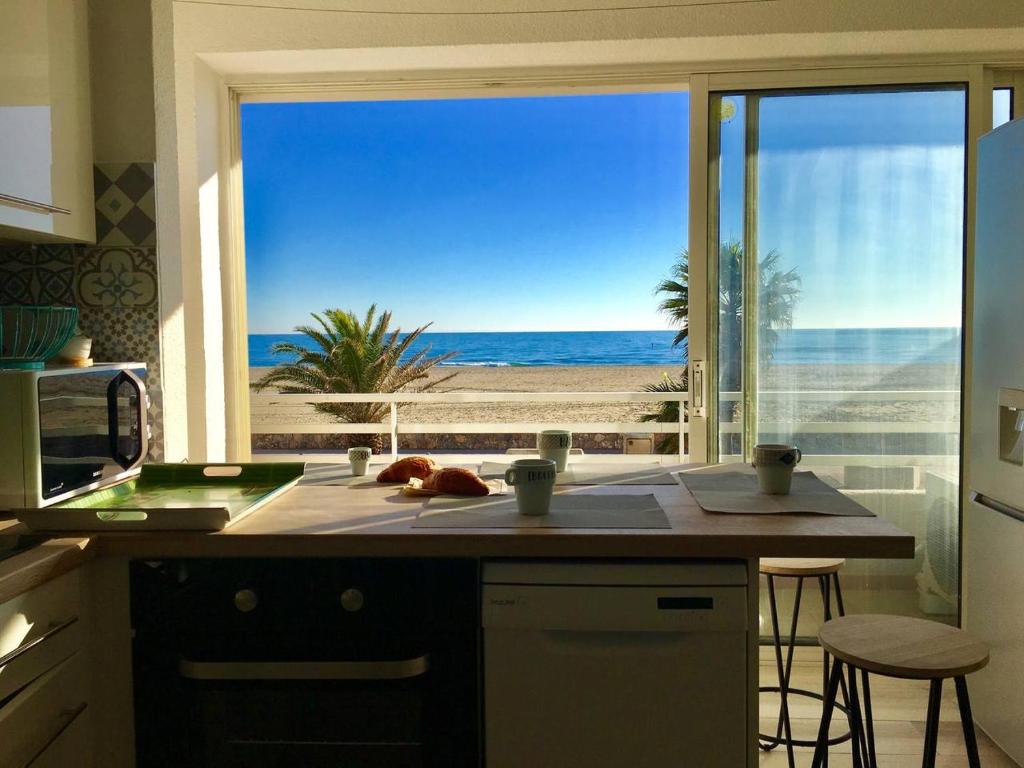 una cocina con vistas a la playa a través de una ventana en "PLAGE" Splendide Vue Mer depuis la chambre et le salon cuisine, 20m de la plage! en Canet-en-Roussillon