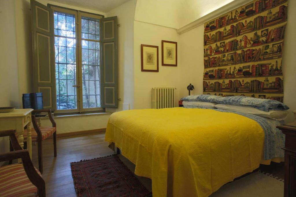 - une chambre avec un lit jaune, un bureau et une fenêtre dans l'établissement Two rooms apartment in Palazzo Malaspina, à Plaisance
