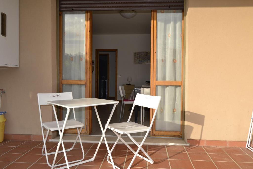 a table and two white chairs sitting next to a window at Via Dante 10 Apartment in Sirolo