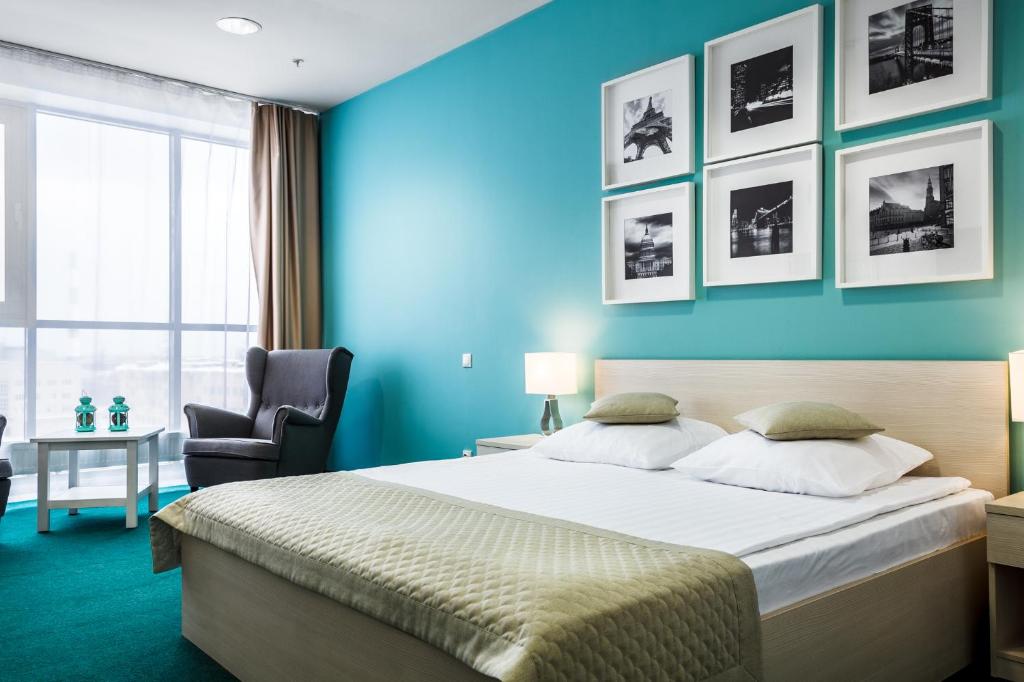 um quarto com uma cama e uma parede azul em Kaskad Hotel em Níjni Novgorod