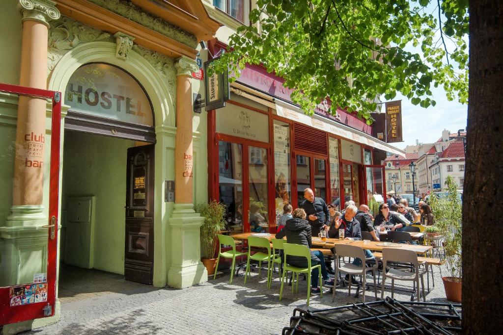 un grupo de personas sentadas en mesas fuera de un edificio en Best Spot Hostel en Praga