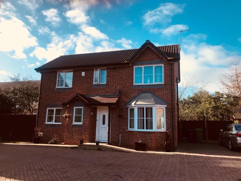 a brick house with a white door on a street at 2 The Mews in Winsford