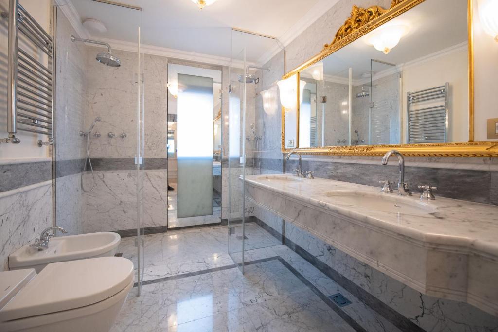 a bathroom with two sinks and a toilet and a mirror at Ca' Bonfadini Historic Experience in Venice