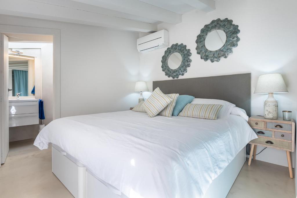 a white bedroom with a white bed and a mirror at Sa caseta Farinera in Sóller