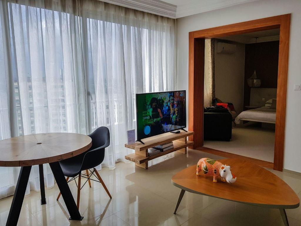 a living room with a table and a flat screen tv at Appartements Lamblin in Abidjan