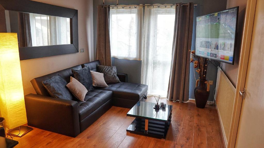 a living room with a leather couch and a tv at North London Apartment - Edmonton in Edmonton