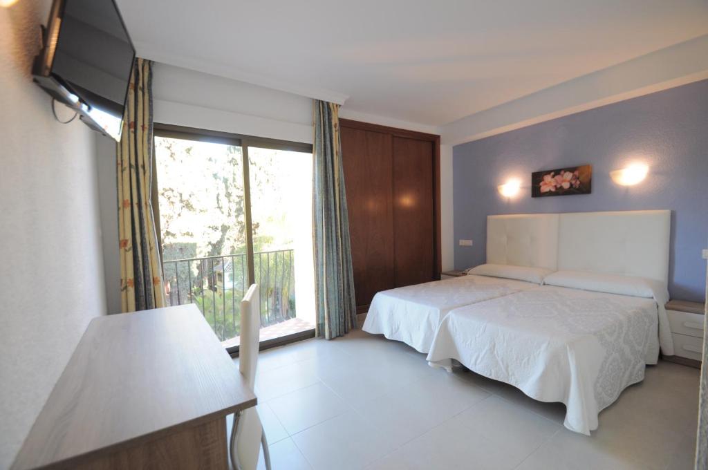 a bedroom with a bed and a large window at Hotel Goya in Almuñécar