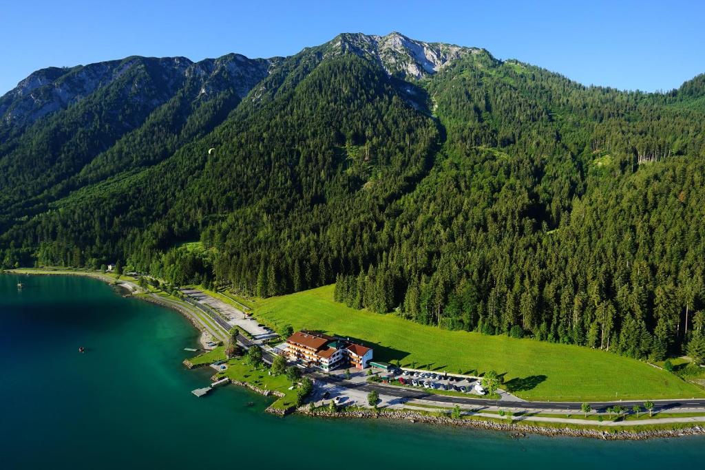 une île au milieu d'un lac avec une montagne dans l'établissement Seehotel St Hubertus, à Pertisau