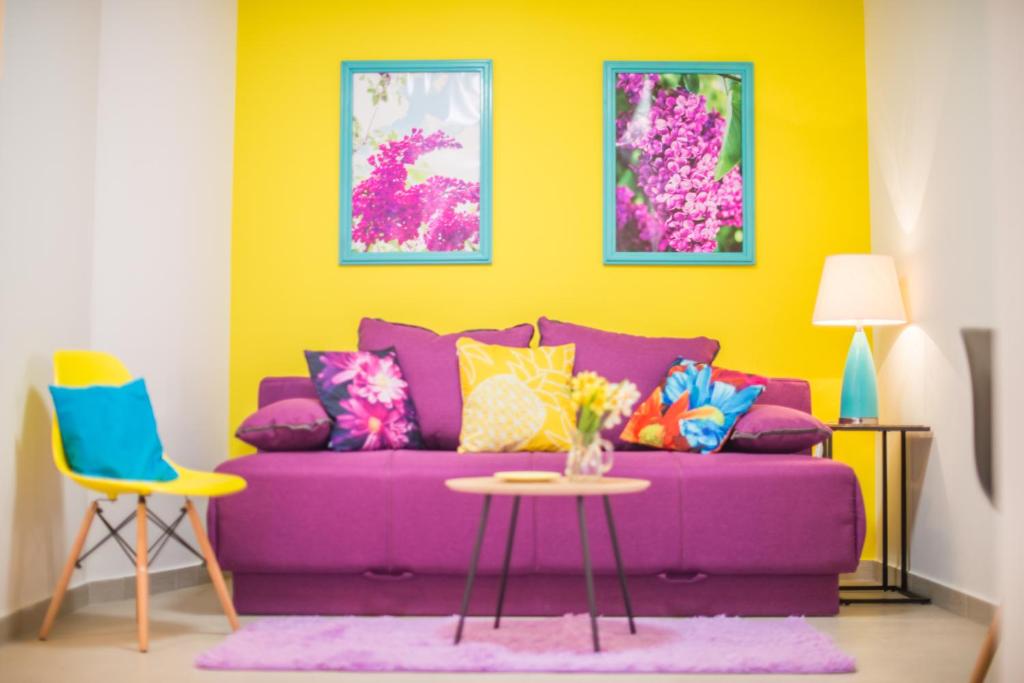 Sofá púrpura en habitación amarilla con mesa en Apartments Canaria, en Pula