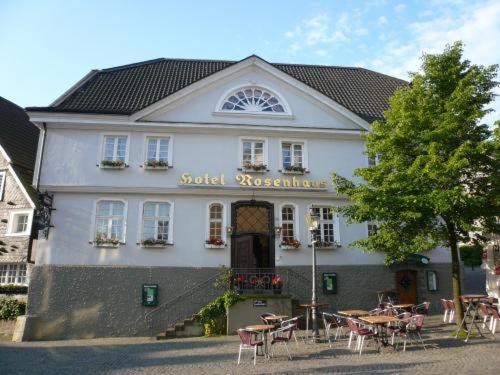 a building with tables and chairs in front of it at Elektro-Hotel Rosenhaus GmbH in Velbert