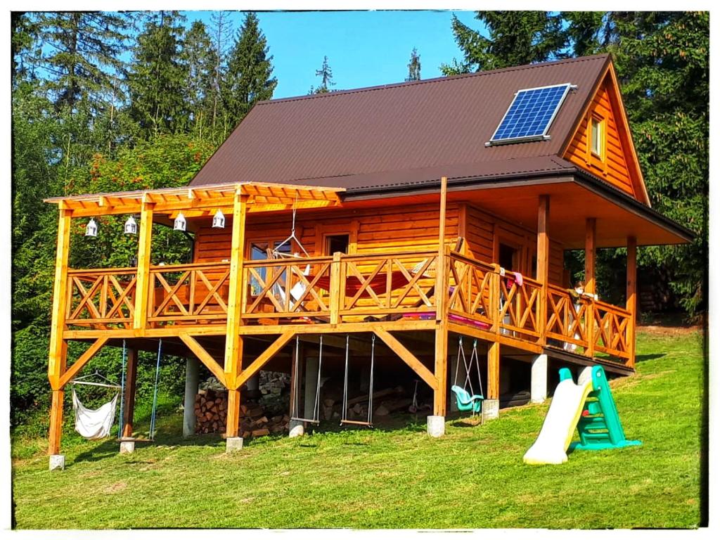 eine große Holzhütte mit einem Sonnendach und einem Spielplatz in der Unterkunft Chata w Górach in Klikuszowa
