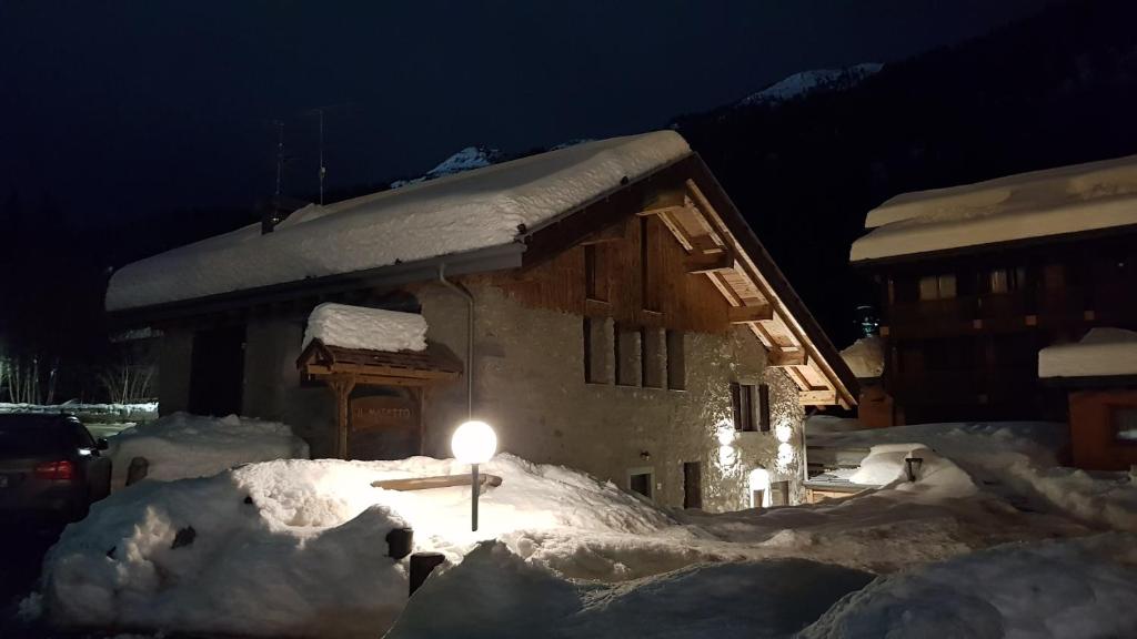 una casa cubierta de nieve por la noche con una luz delante en Masetto en Madonna di Campiglio